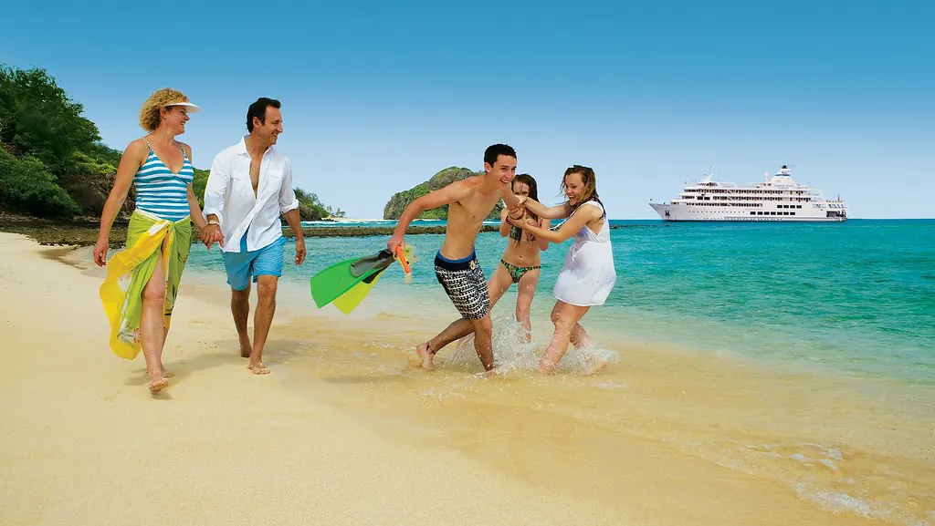 Family enjoying a beach holiday with a cruise ship offshore, travel and leisure sector