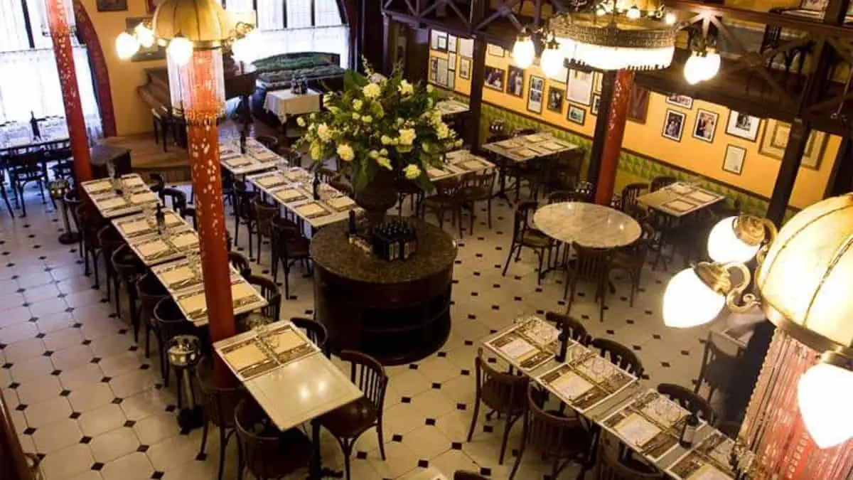 Comedor de un restaurante clásico con mesas preparadas y lámparas de araña